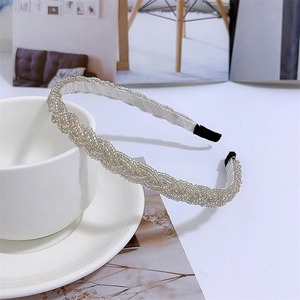 Detail of beaded braided headband with pearls on white ceramic plate for elegant hair styling
