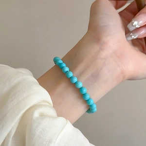 Detail of beaded turquoise stretch bracelet with sky blue round stones on woman's wrist