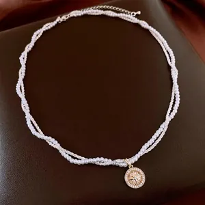 Collana a strati placcata oro con perle sintetiche e un ciondolo a bussola stellata
