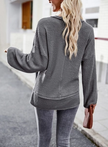 Back view of a grey waffle-knit long sleeve top featuring a loose fit and casual hemline