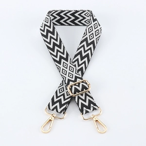 Detail of adjustable black and white geometric embroidery bag strap with gold metal clips