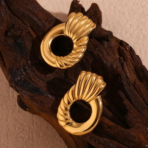Macro detail of 18K gold plated hoop earrings with textured finish on wood