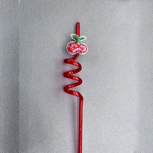 Detailed close-up of a red spiral plastic straw featuring a glittery cherry pendant