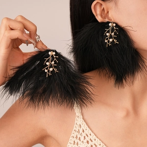 Boucles d'oreilles ethniques en plumes noires avec branches dorées et perles sur modèle