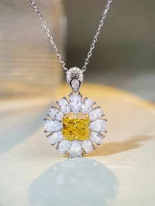 Macro shot of yellow cushion-cut gem flower pendant with pear-shaped halo on silver chain