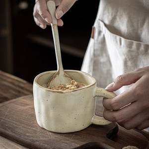 Handcrafted ceramic mug set in cream finish with spoon and rustic oatmeal scene