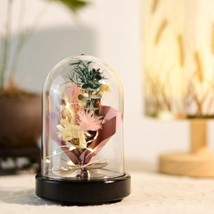 Close-up of preserved flowers in a dome with LED lights and a pink ribbon