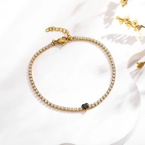 Détail d'un bracelet tennis doré avec zircons et une pierre en forme de cœur noir