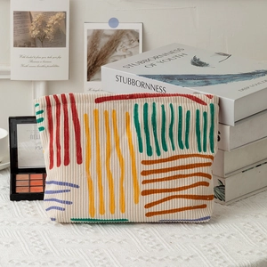 Detailed close-up of corduroy cosmetic bag with colorful embroidered abstract patterns