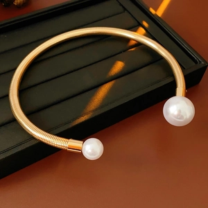 Close-up of golden textured metal open necklace featuring two elegant white pearls