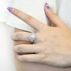 Close-up of a silver halo zircon ring with oval center stone on a woman's hand