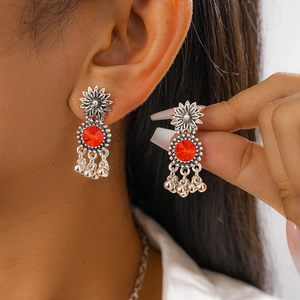Detail of vintage silver flower earrings with red gemstone and metal tassel fringes