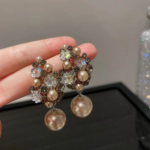 Macro shot of floral cluster earrings with champagne pearls and sparkling rhinestones