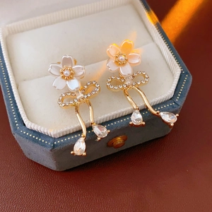 Détail macro de boucles d'oreilles fleur et perle avec nœuds strass en boîte à bijoux