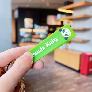 Close-up of green silicone Panda Baby keychain strap with 3D letters and gold metal ring