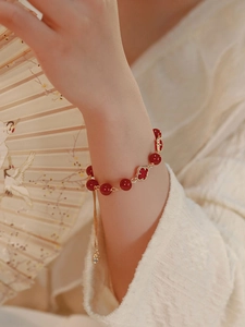 Detail view of red beaded flower bracelet with adjustable gold chain on wrist
