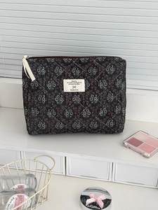 Dettaglio della borsa da trucco in velluto nero con motivo floreale e cerniera