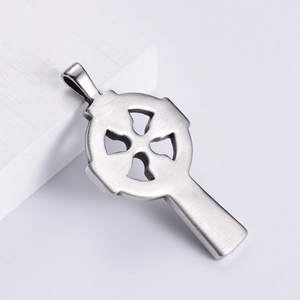Polished silver stainless steel Celtic knot cross pendant in a minimalist studio setting