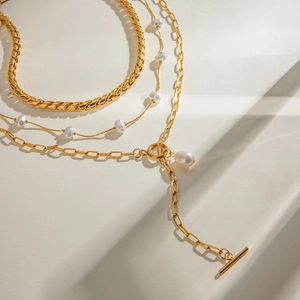 Collana multistrato in acciaio dorato con ciondolo di perle e chiusura a levetta