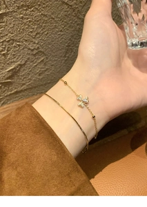 Detail of 18K gold plated clover bracelet set with sparkling cubic zirconia on model wrist
