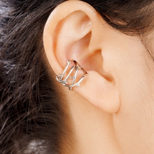 Dettaglio macro di earcuff a spina in argento stile punk su orecchio di modella