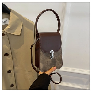Close-up of brown PU leather crossbody bag with pattern patchwork and silver clasp