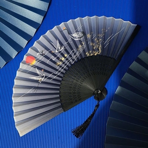 Detail of blue crane fan with red sun pattern, black frame and elegant tassel
