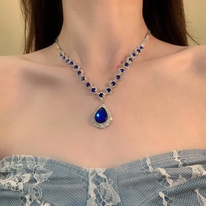 Macro view of teardrop blue gemstone pendant with sparkling zircon floral accents