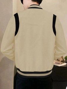 Back view of a casual baseball jacket with beige body and black shoulder contrast
