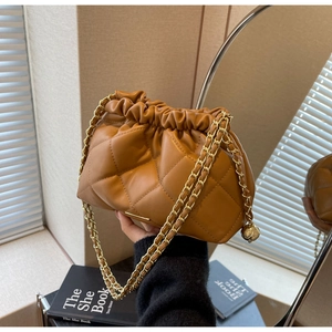 Close-up of quilted brown leather bucket bag with gold chain and adjustable metal ball