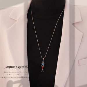 Detailed view of long gold koi fish pendant with colorful enamel on a pink blazer