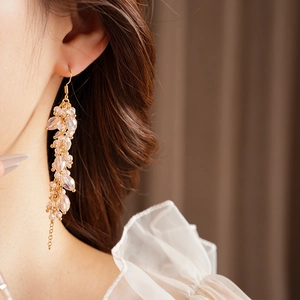 Close-up of bohemian gold long earrings with pink crystal beads on model with soft lighting