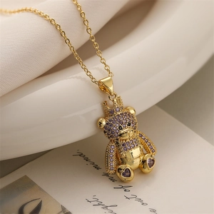 Macro view of teddy bear pendant with crown and purple crystals on a gold chain