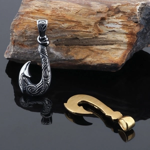 Vintage stainless steel fish hook pendants in silver and gold on a dark rock background