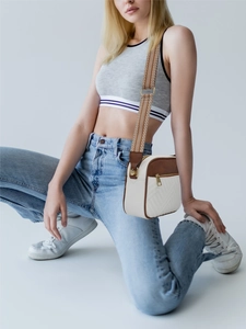 Detail of vintage quilted crossbody bag with cream body and caramel brown trim on a model