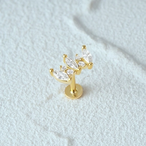 Macro view of gold crown piercing stud with marquise cubic zirconia on white stone
