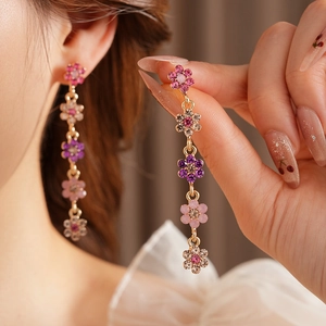 Detailed view of dangling flower tassel earrings with pink and purple rhinestones