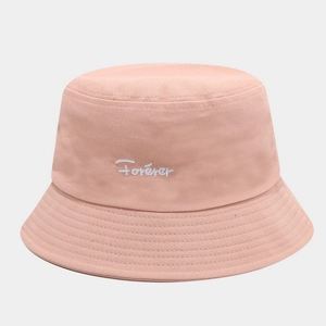 Détail de la broderie Forever blanche sur le tissu en coton rose du chapeau bob