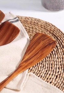 Detailed close-up of natural ebony wood spatula with smooth grain on a textured rustic mat