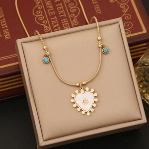 Détail du pendentif cœur doré avec nacre et perles turquoise sur une chaîne serpent fine