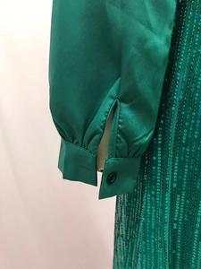 Detail of satin green cuffs and shimmering sequin mesh fabric on elegant v-neck shirt