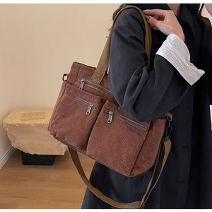 Brown corduroy shoulder bag with multi-zipper pockets shown in casual lifestyle setting