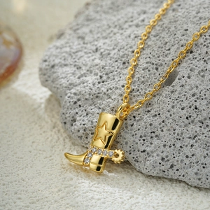 Macro shot of 18K gold plated cowboy boot pendant with zircon stars on volcanic rock