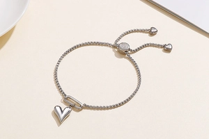 Detail of adjustable silver stainless steel heart bracelet with shimmering slider clasp