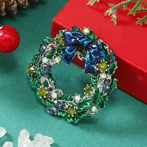 Detailed view of Christmas wreath brooch with green holly leaves and blue enamel bow