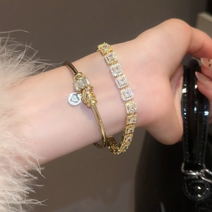 Détail de l'ensemble de bracelets dorés avec breloques zircon et chaîne tennis cristal