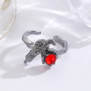 Macro shot of gothic raven ring with intricate feathers holding a vibrant red bead
