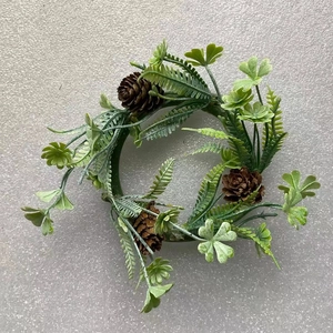 Mini Christmas wreath featuring green fern leaves and natural pine cones on gray surface