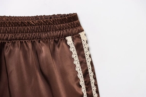Primer plano de los pantalones cortos de satén marrón con cintura elástica y encaje blanco