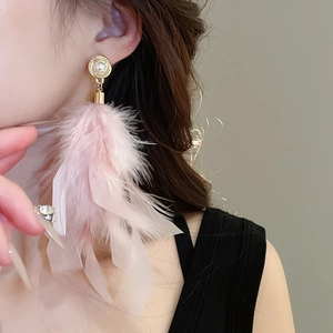 Detail of pink feather drop earrings with gold metal and pearl stud worn by model